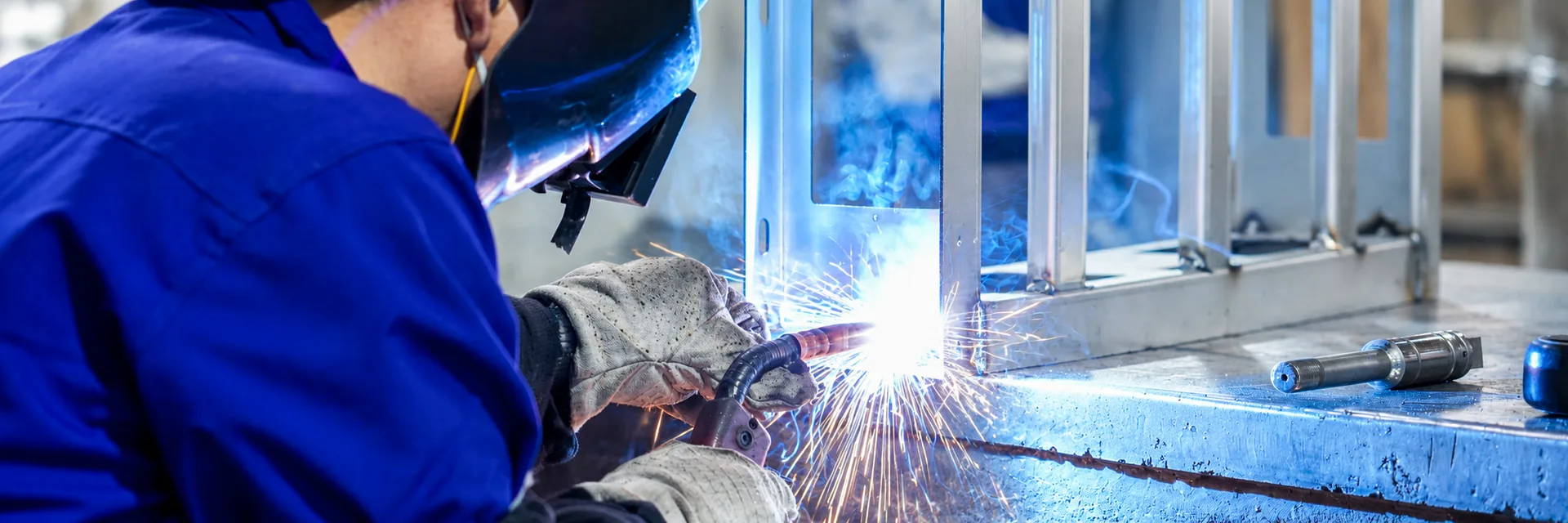 Worker wearing protective equipment while welding a metal equipment frame
