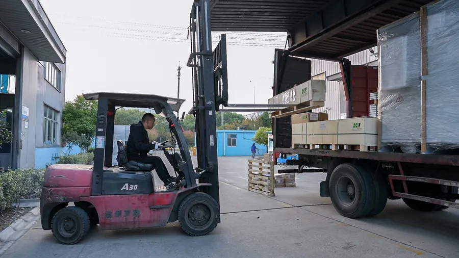 Forklift loading packaged equipment onto a delivery truck