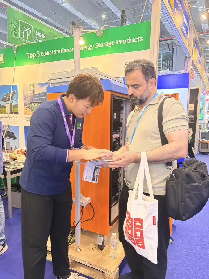 Huijue Group representative discussing a telecom site energy cabinet with a visitor