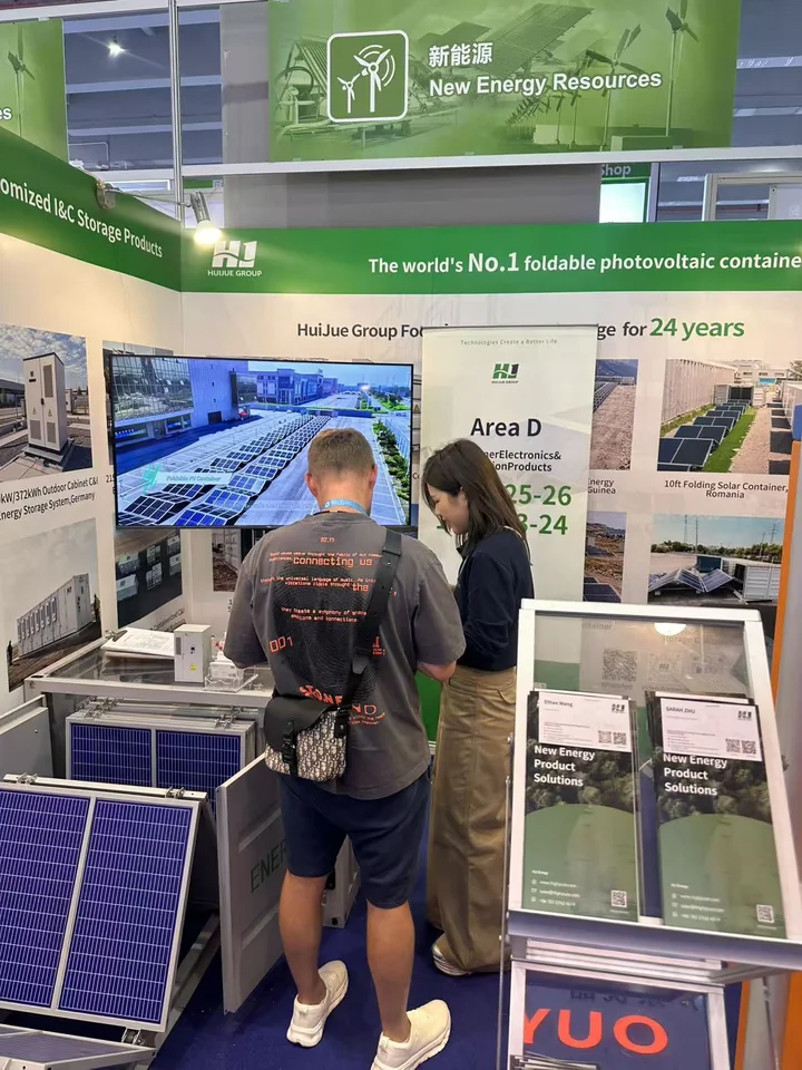 A visitor discussing foldable photovoltaic-container models with the Huijue Group exhibition team